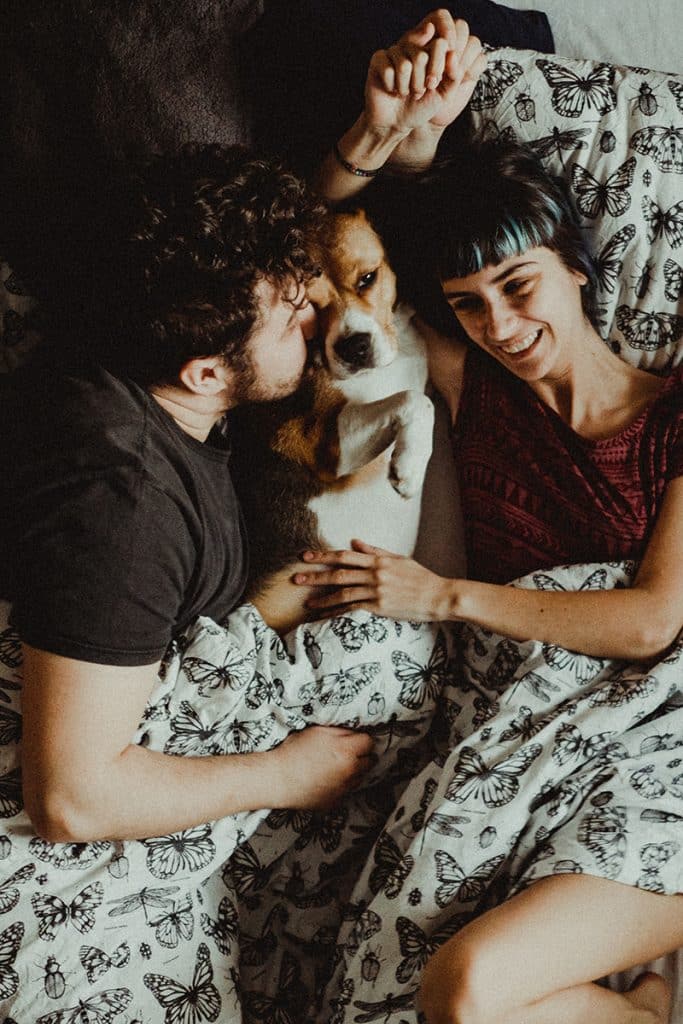 happy couple is kissing their dog after he climb into the bed using the dog steps with no trouble at all
