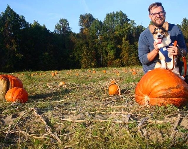 happy dog and is owner taking photo together in a pumpkins field