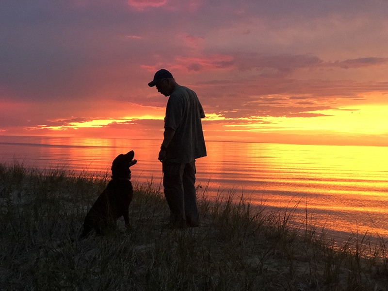silhouette of a man and his dog at sunset